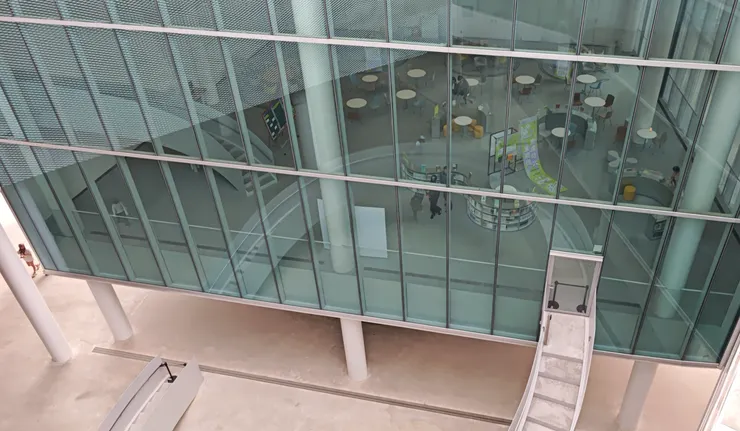 台中綠美圖:玻璃欄杆與挑空設計讓各樓層視線相互穿透，下方的階梯與圓桌閱讀區清晰可見