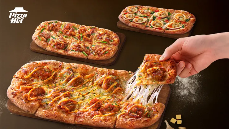 必勝客「手工義式薄比薩」重磅回歸！不僅延續職人手工拉製的27cm 橢圓造型餅皮，更帶著餡料豪邁加量50%的誠意，一口氣發表三款全新口味。