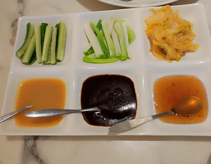 上排左至右，小黃瓜、蔥白、黃金泡菜；下排左至右，味增醬、甜麵醬、金桔醬