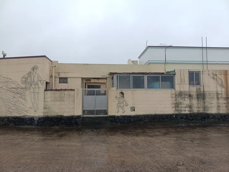 「親子」牽手的地方剛好是門的位置，把牽手的圖樣放在角落，是溫馨畫面呢？還是...，很有幽默感的作品。