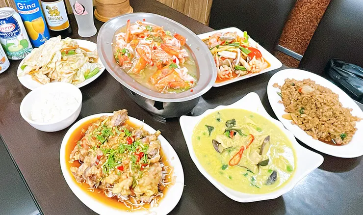 桌面擺滿泰式料理，包含檸檬蝦、綠咖哩雞、打拋豬、椒麻雞與冷飲。