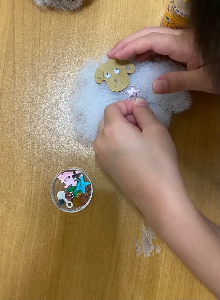 以保麗龍膠把羊頭黏在綿花上,兩條羊腿斜黏在羊身下方,並讓小朋友自由選用亮片裝飾綿羊。