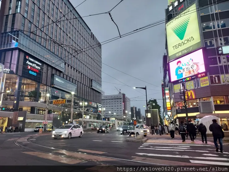 傍晚的薄野街頭，飄著微雨，天氣微涼，路人也都是穿長袖衣服或加上外套。