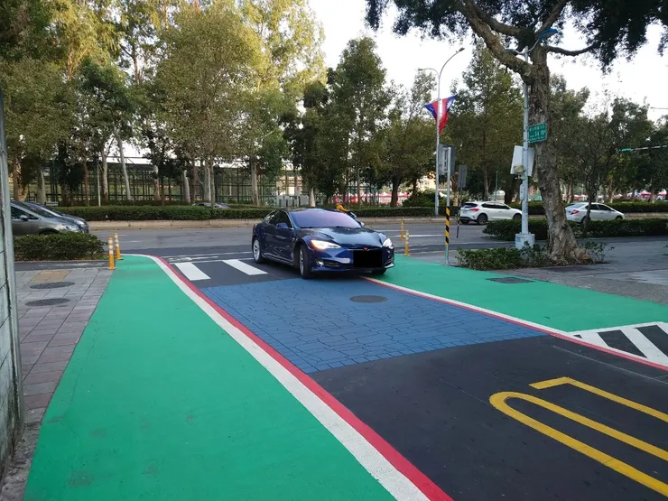 新生南路三段54巷口的「入口意象」。在沒有實體區隔的情況下，車子過頭，壓到了交通安全協會盛讚的突出範圍。國旗下方的牌面，其實就是「交通友善區」的牌面。這個長官牌面跟新加坡的不一樣，沒有面對車流方向，是給長官看的。