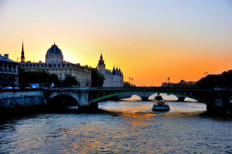 【塞納河觀光船往復岸邊遊人消閑！圖中橋名「新橋」（Pont Neuf），卻是是巴黎塞納河上最古老的橋樑，建於1578年至1603年間。  背景的主要建築物為巴黎司法廳（Palais de Justice）和聖禮拜堂（Sainte-Chapelle）的圓頂，都在西岱島（Île de la Cité）上。】