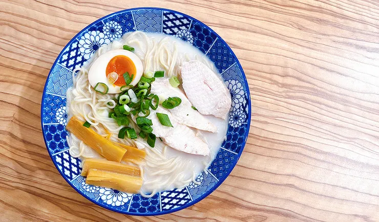 小白拉麵雞豚白湯拉麵俯視特寫，乳白色濃郁湯頭搭配舒肥雞肉、溏心蛋與木耳，視覺豐富澎湃。