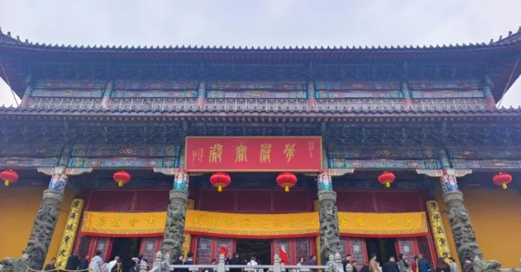 旃檀林的正面,紅色匾額上寫著「開光大吉」,黃色的大門口掛著紅燈籠,旁邊的雕像與細緻的建築細節令人印象深刻。