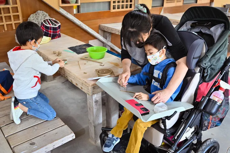 玩陶土需要照顧者協助握著手參與的祐。