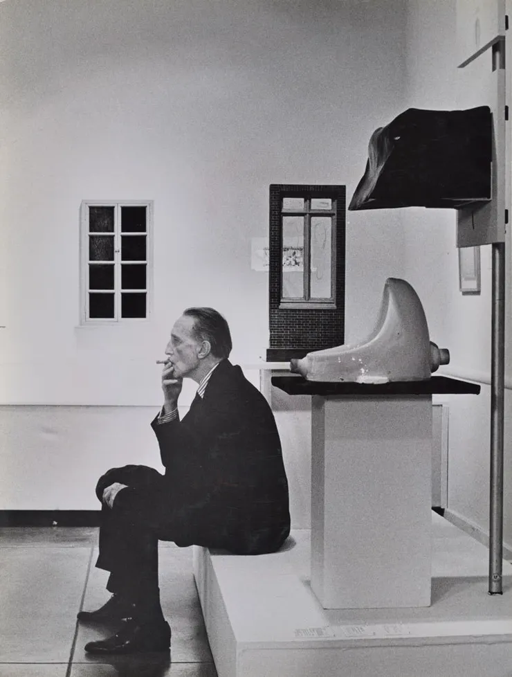 Duchamp smoking in front of Fountain, Duchamp Retrospective, Pasadena Art Museum, 1963