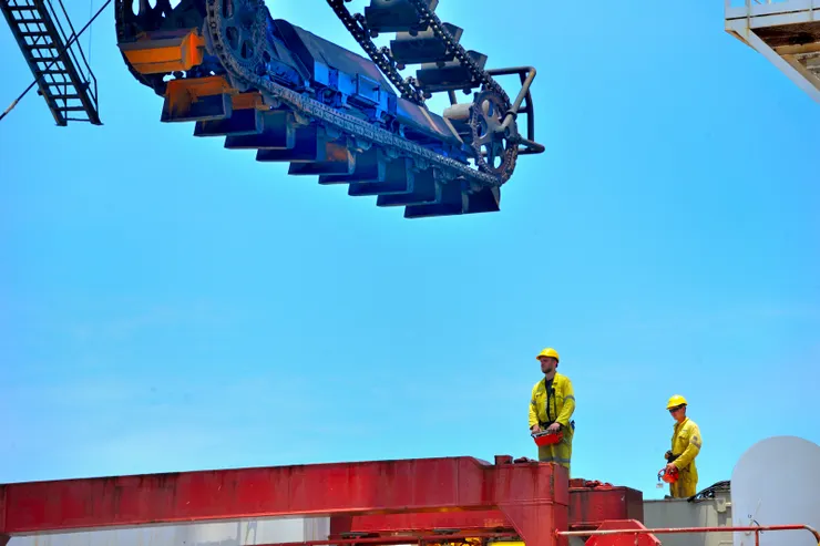 【海吊船技師操作吊桿,準備將卸煤機移至岸上。】
