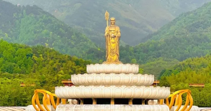 大願文化園區,金色佛像矗立在潔白的蓮花座上,背景是青山綠樹,展現出寧靜且莊嚴的景觀