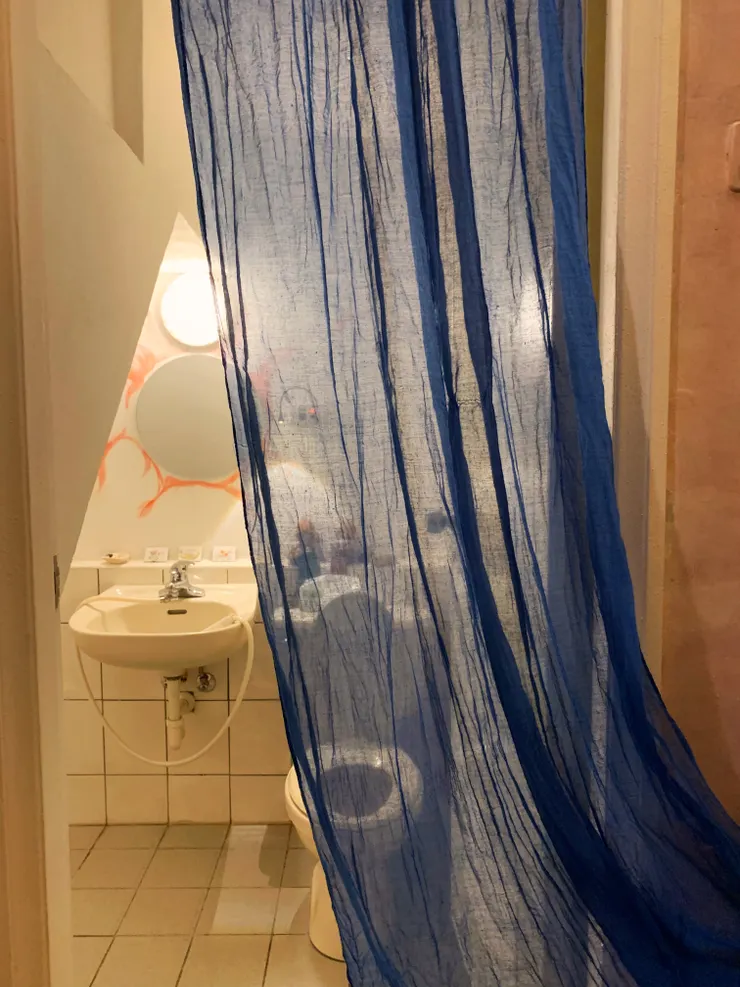 廁所門前掛上一塊透光的紗布，讓廁所維持通風，又不會直接看到裡面。鏡子手繪像是太陽的圖騰，搭配主照明與間接照明，讓廁所彷彿有了自己的靈魂。