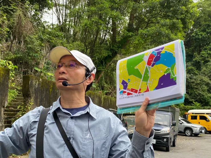 何文賢老師說明辛亥路四段的土地使用計畫。後方山坡原預定興建辛亥國中與辛亥高中，但因少子化導致需求降低，最終取消。