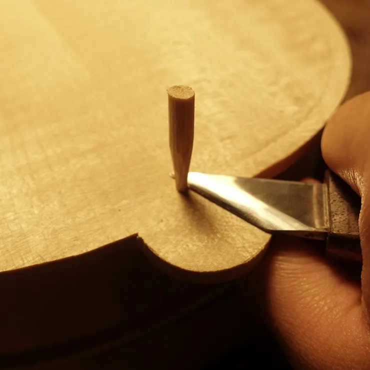 這是在進行鑲線（purfling）之前，先將側板框與琴身的定位孔填補起來。這些定位孔是在製作過程中用來固定與對齊琴身結構用，但在完成主體後，製琴師會細心修補，使外觀更加完整，確保鑲線能夠順利且精確地嵌入。