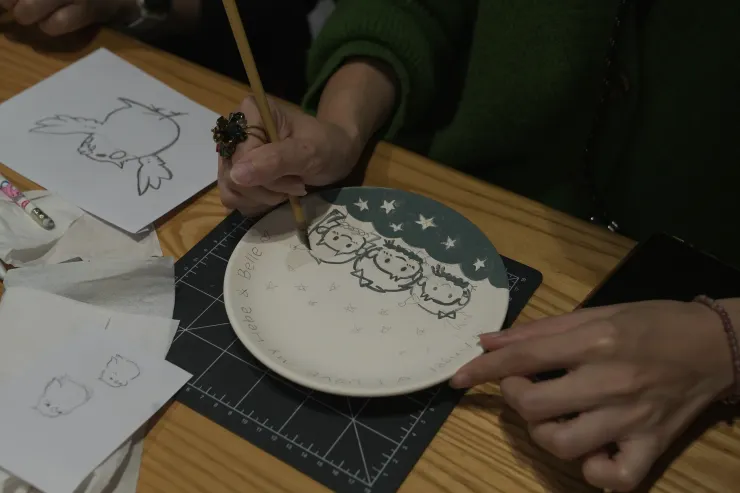 遊客正小心翼翼地在白色瓷盤上彩繪。(攝影/曾耀玄)