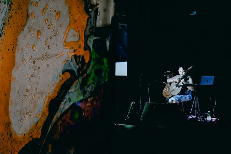 陳崇青於「2023世界音樂節@臺灣」登台演出，與液態光藝術家白油合作，現場以彈撥樂器演奏，共同打造音樂與視覺藝術的交融之美。（圖／風潮音樂提供）