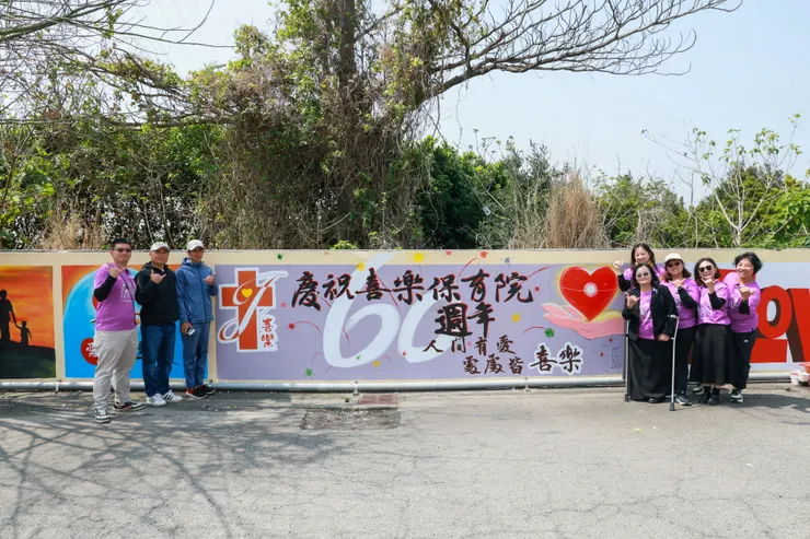 莊進益大師日前參加喜樂保育院60週年萬合院區圍牆彩繪活動,與院長林玉嫦一同在其作品邊合影留念。