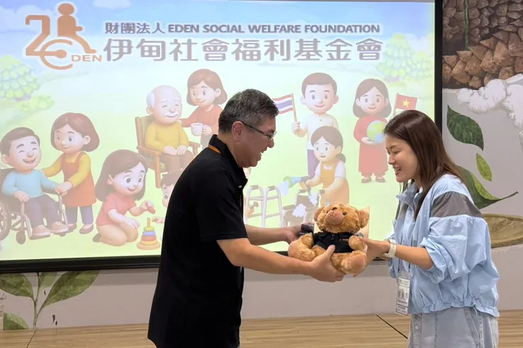 （圖說：伊甸新北市坪林水柳腳公共托老中心主任洪肇元(左)贈送見面禮予韓國高齡人力開發院代表。）