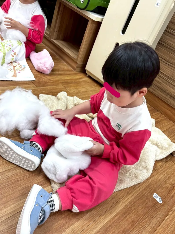 孩子很認真的為自己的枕頭塞入棉花