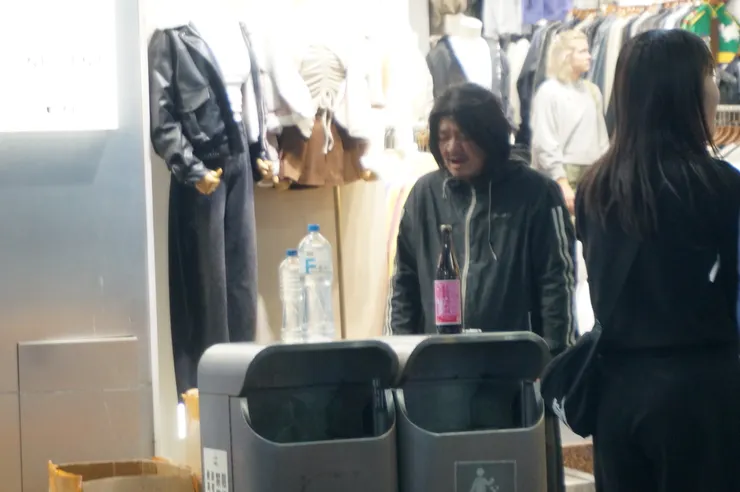在西門町中，一個站在垃圾桶旁的人