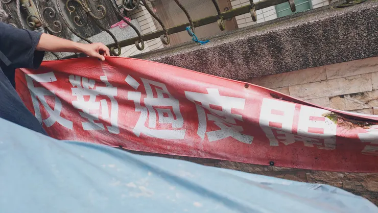 住戶仍將當年抗爭的紅布條掛在牆外。布條寫的是：反對過度開發，還我寧靜社區