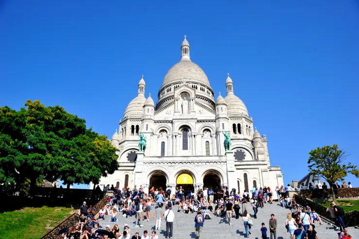 【白色聖心堂遊客如潮小販叫賣忙！蒙馬特山丘上的聖心堂（Basilique du Sacré-Cœur de Montmartre），結合羅馬式與拜占庭式建築風格，位居巴黎最高點，可俯瞰市區。】