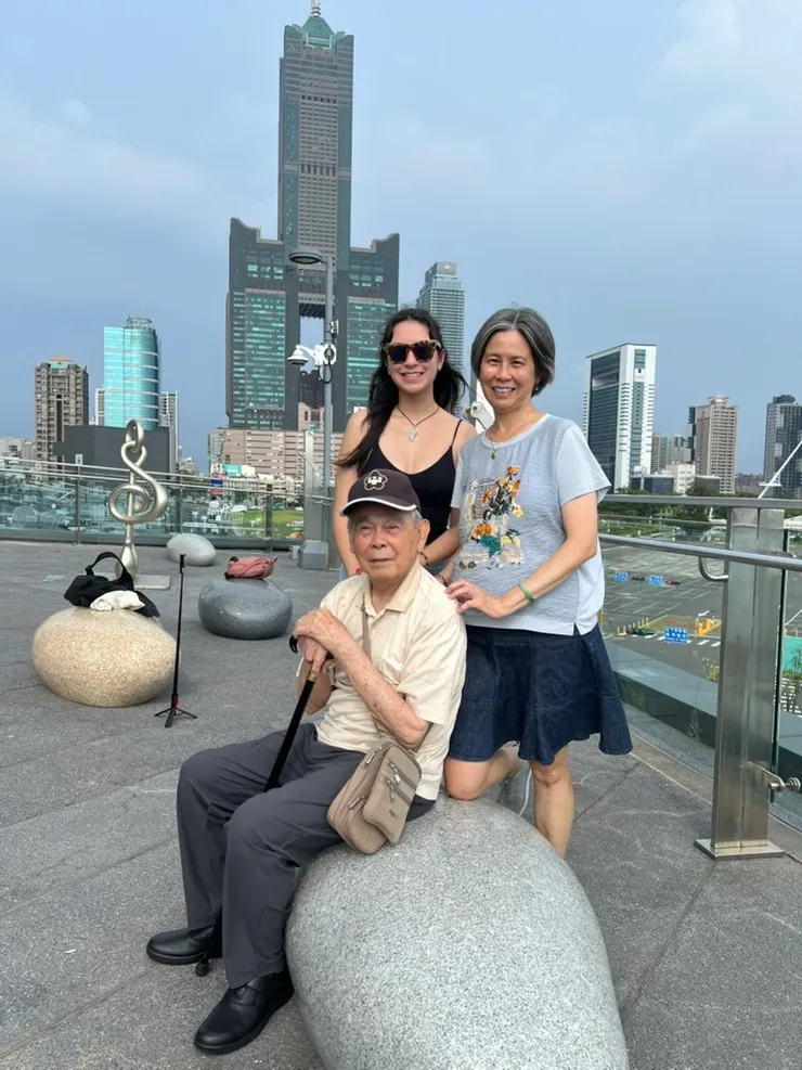 我和以柔跟爸爸合照，左後方有一個高音符號和船錨組合的雕像