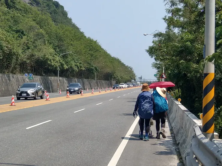 母女二人組包緊緊，揹著背包推著推車徒步環島。適逢連續假日，共構路段終點處開始塞車。