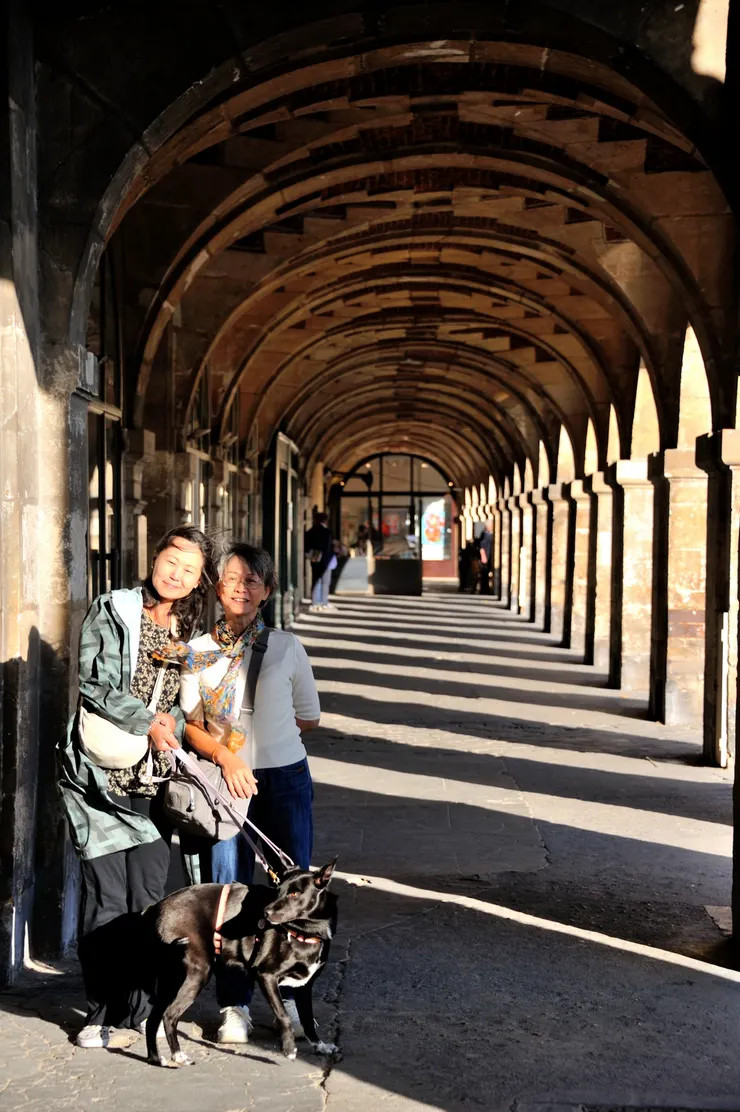 【孚日廣場四周建築對稱雨果曾居！兩人一狗在紅磚拱廊前。】