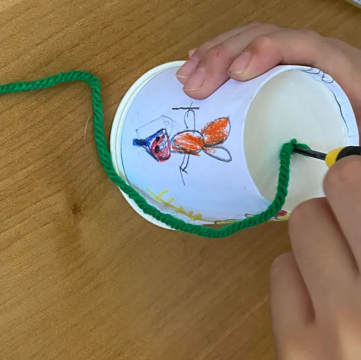 穿線的技巧是拿戳洞的尖頭小工具，把線戳進去。用尖一點的鉛筆也可以唷！注意紙別碰到杯緣捲邊喔！