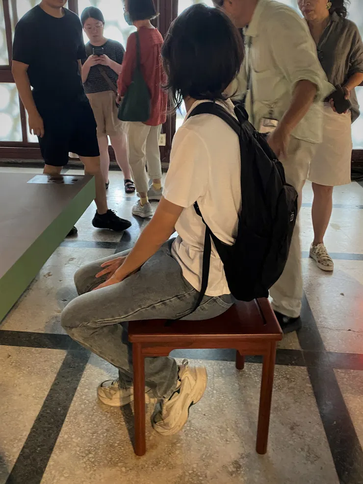 徐明松老師讓參加導覽的民眾試坐餐凳