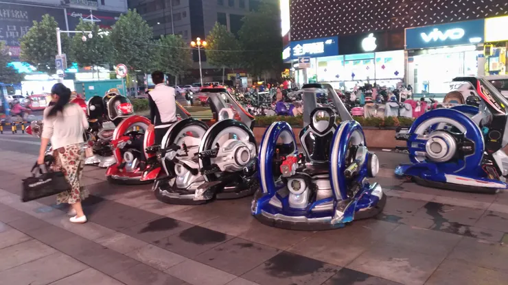 廣場上出現各種新奇機器玩具，閃著燈、會互動，孩子追著跑，大人也忍不住停下來玩兩把，科技與童趣交織，讓人一秒找回久違的快樂。