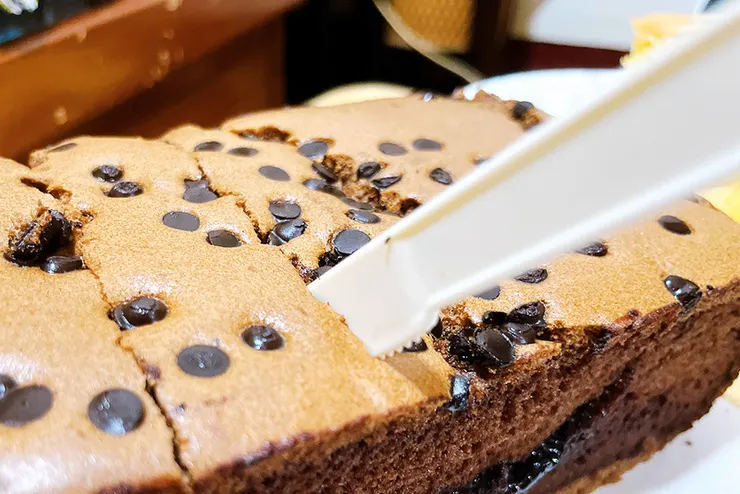 裝在金黃色質感禮盒中的初蛋糕巧克力口味，側面展現出紮實且濕潤的糕體，與表層的大量巧克力豆形成鮮明層次，適合送禮推薦。