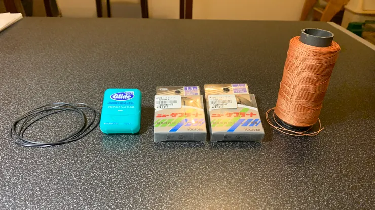 由左至右的皮帶材料：原廠橡膠皮帶、牙線、1.5 號與 4 號聚芳酯纖維釣魚線、不知名纖維線