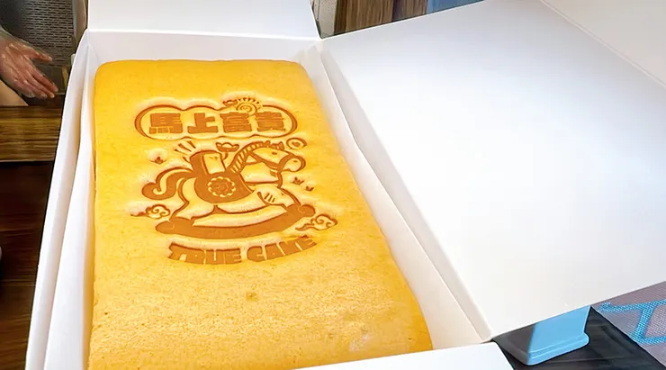 原味豆漿蛋糕金黃色表面特寫，清晰可見「初蛋糕」品牌字樣與 Logo 烙印，象徵堅持天然原料的職人品質。