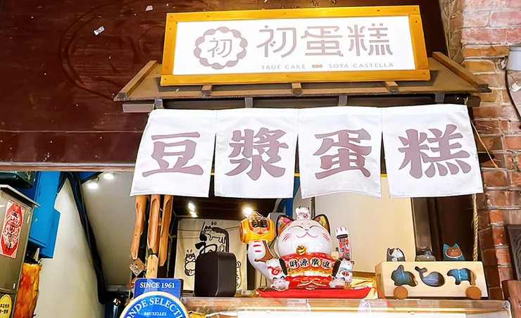 三峽老街甜點美食「初蛋糕（True Cake）」店面，招牌主打豆漿蛋糕，櫃台擺放可愛的招財貓與木造裝飾，展現職人烘焙的文青風格。