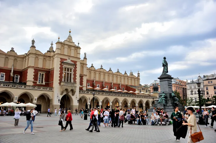 【詩人亞當銅像下男男女女喜相見！右側可見亞當·密茨凱維奇紀念碑 (Adam Mickiewicz Monument)，是波蘭最著名的紀念碑之一，青銅雕像為浪漫主義詩人亞當·密茨凱維奇，建於 1898 年，底座周圍有四組寓意雕塑，分別代表祖國、科學、勇氣和詩歌。許多人到中央市集廣場會約在這裡碰頭。】