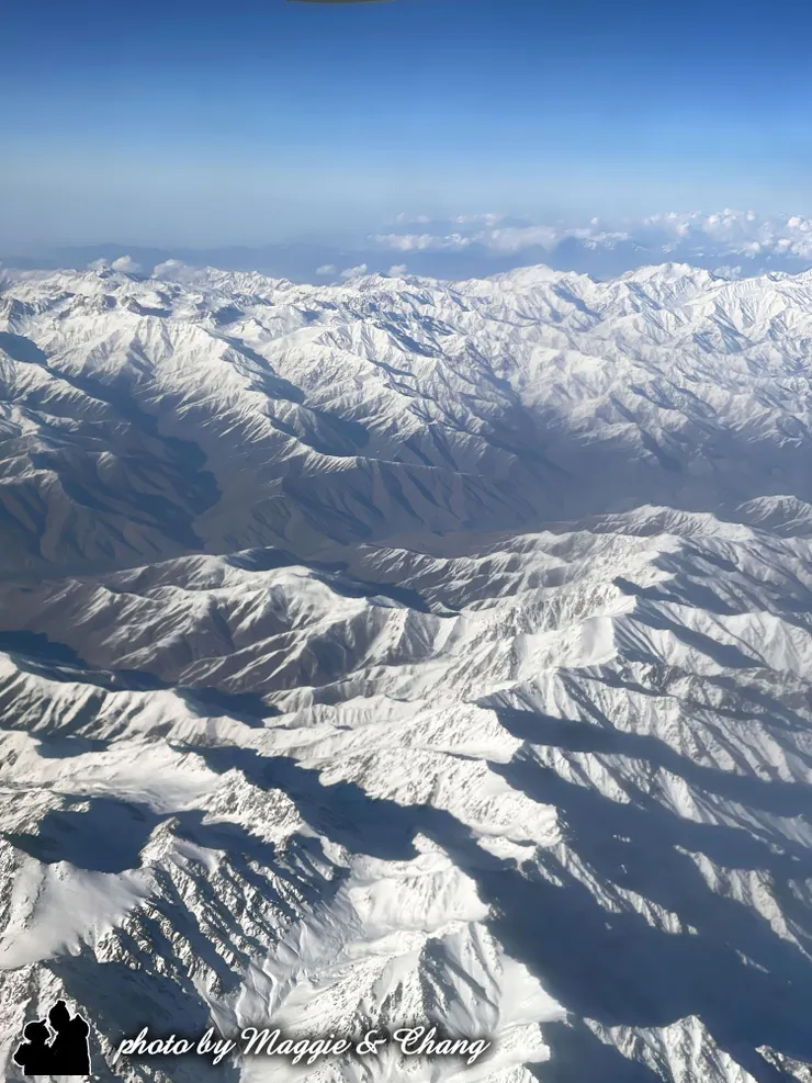 飛越中亞、阿富汗和塔什干一帶時，窗外的景色令人屏息——遠方是一望無際的高原與山脈，覆滿皚皚白雪的山巒像是揉皺的銀色地毯，在陽光照射下閃爍著淡金色的光芒。山脊間的陰影深邃而神秘，彷彿是某種被時間遺忘的國度。