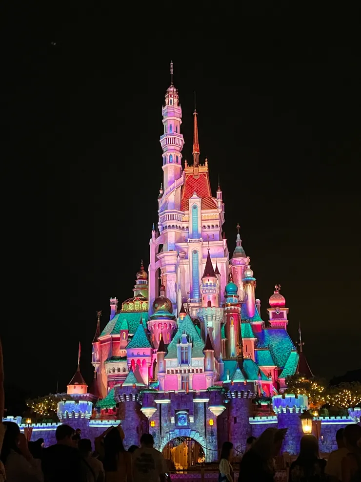 夜晚的迪士尼城堡與等待燈光秀的遊客。
