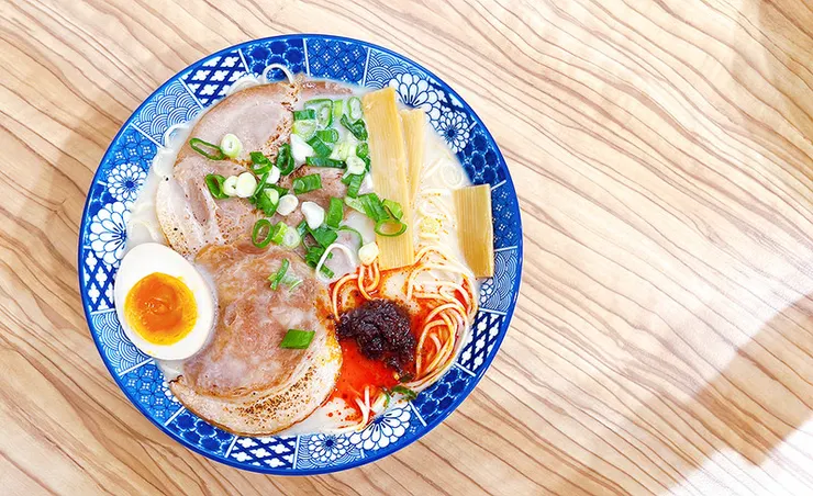 小白拉麵麻辣豚骨拉麵全貌，碗內鋪滿大片炙燒叉燒、溏心蛋、木耳與蔥花，展現豐富澎湃的視覺震撼