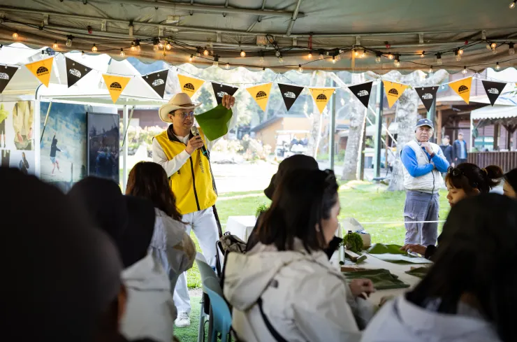 愛上喜翁營地的蔡董正在教大家如何正確地用香蕉葉包飯