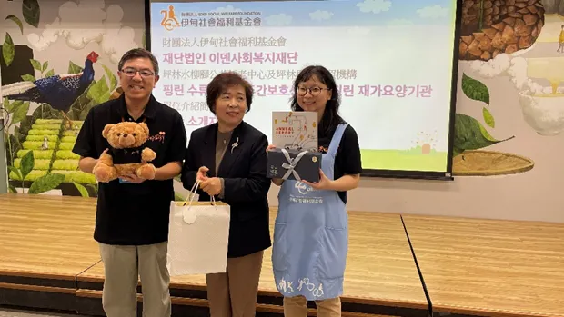 坪林水柳腳公共托老中心主任洪肇元(左)與韓國參訪團代表(中)致贈見面禮。