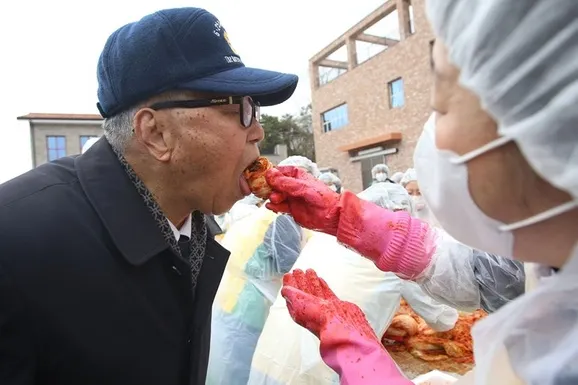 11月29日，於坡州市多米索爾食品公司舉行的新天地西門枝派結業紀念特別志工服務中，出席活動的韓戰參戰有功人士品嚐辛奇的情景。
