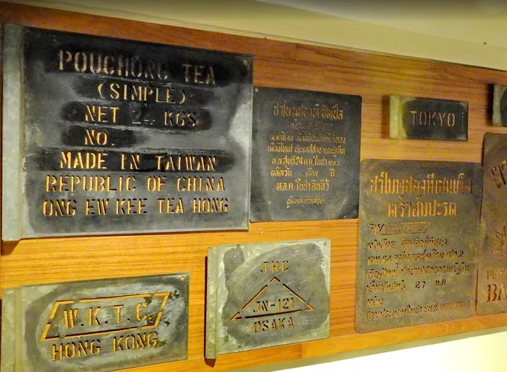 牆上的金屬銘牌，是最動人的歷史筆記。「POUCHONG TEA（包種茶）」「MADE IN TAIWAN」「ONG EW KEE TEA HONG」，還有「HONG KONG」「OSAKA」「BANGKOK」的字樣，拼出了一張台灣茶的外銷版圖