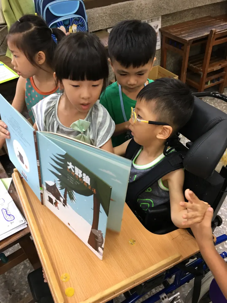 小女孩講故事，其他孩子會牽子祐的手。