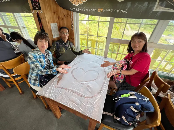 服務生手指沾水在桌上畫愛心， 再鋪上塑膠桌墊。