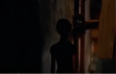 延續上一個鏡頭，鏡頭緩緩地跟著蘇麗珍移動，燈光灰暗，只見她身形剪影下樓梯往麵攤移動。