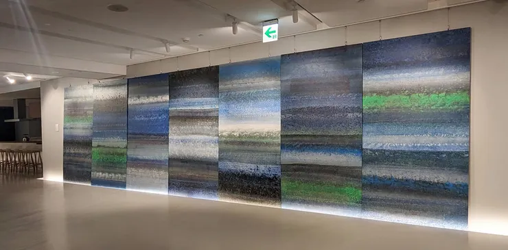 積吶虹光，〈海〉，2019年，壓克力顏料、紙，840 X 244 cm。維吉尼亞•吳爾芙(Virginia Woolf）：起初，藍色的海浪有節奏地拍擊，將海灣染上一片藍色，令人心曠神怡，好似身體隨波漂流，只是轉瞬之間，洶湧波濤的黑色浪尖卻叫人心中一凜，寒意頓生。 隨後，幾乎每個傍晚，一股白色的泉水都會從那塊黑色巨礁的後面噴薄而出。由於出現時間不定，人們不得不靜待守候，在它出現時，喜不自勝；在灰白色、半圓形的海灘上等待時，你會看到，一波接一波的海浪，一次又一次流暢地蛻下一層層珍珠母似的光彩。