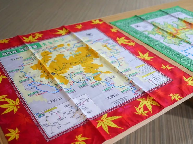 登山口附近店家販售的頭巾,每條費用約台幣100元左右。紅色為山林廳行政管轄範圍,綠色為智異山國家公園。建忠笑說可以直接當離線地圖使用。(黃思維攝影)