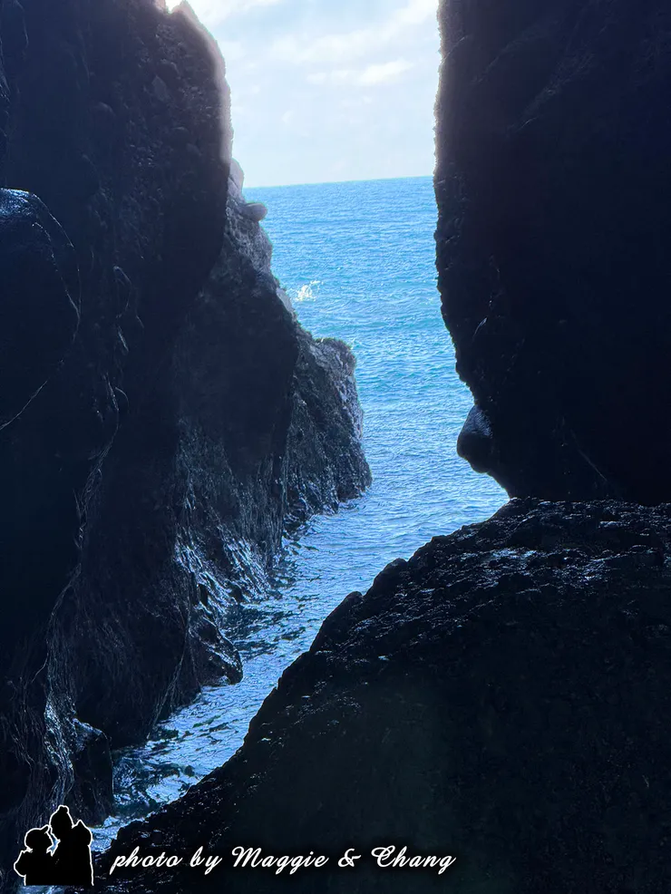 湛藍的天空映著潔白的雲，海浪一波接一波拍打岩石